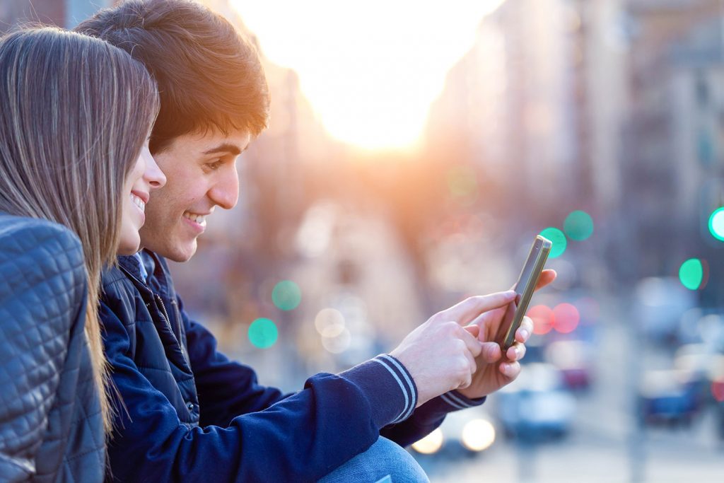 two young people watching their phone city